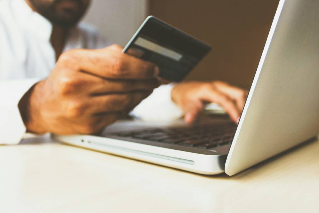 person holding credit card while using computer